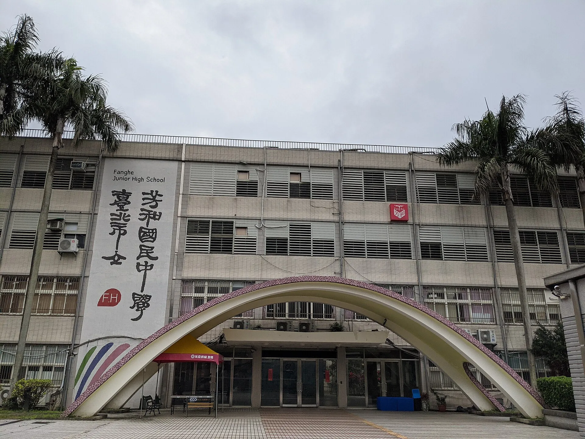 芳和正門的白色拱門和校舍，牆上寫著改名前的校名「臺北市立芳和國民中學」